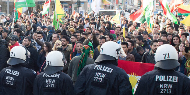 Eine Menschenmenge steht vor einer Polizeikette Eine Menschenmenge steht vor einer Polizeikette