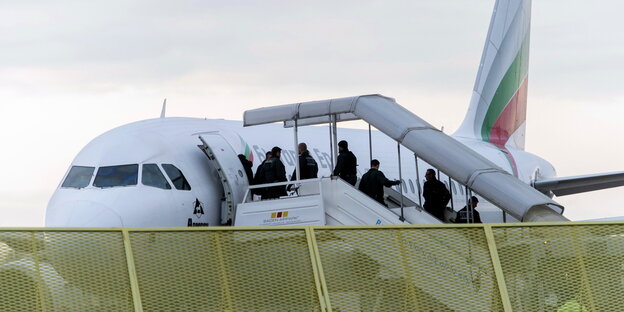 Menschen besteigen über eine Gangway ein Flugzeug