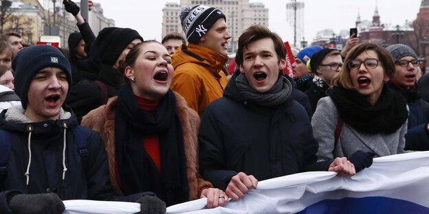 Junge Leute mit russischer Fahne laufen gemeinsam Junge Leute mit russischer Fahne laufen gemeinsam