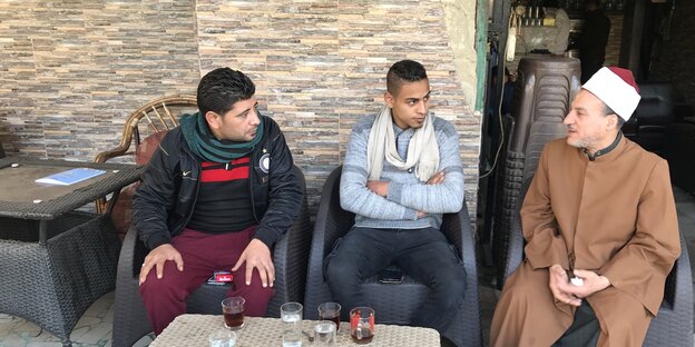 ein muslimischer Gelehrter sitzt neben zwei Jungs in einem Café ein muslimischer Gelehrter sitzt neben zwei Jungs in einem Café