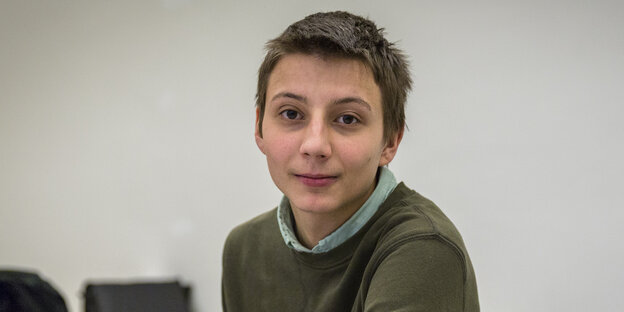 Ein junger Mann mit kurzen hellbraunen Haaren, einem grünen Hemd und einem dunkelgrünen Pullover darüber. Ein junger Mann mit kurzen hellbraunen Haaren, einem grünen Hemd und einem dunkelgrünen Pullover darüber.
