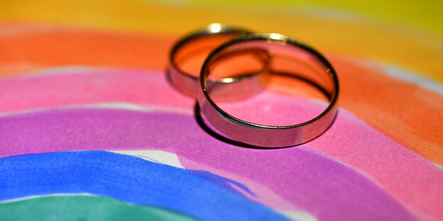 ein getuschter Regenbogen, auf dem zwei Eheringe liegen ein getuschter Regenbogen, auf dem zwei Eheringe liegen