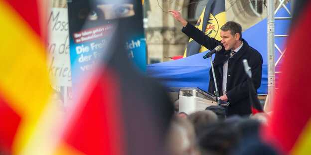 Björn Höcke spricht an einem Rednerpult im Freien, davor stehen Menschen mit Deutschlandfahnen Björn Höcke spricht an einem Rednerpult im Freien, davor stehen Menschen mit Deutschlandfahnen