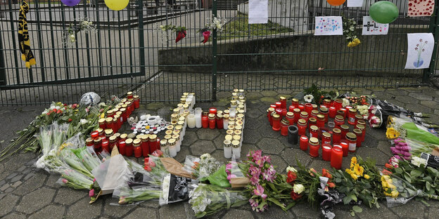 Vor dem Schultor liegen Blumen und Kerzen in Form der Initialen des Getöteten, L.H.