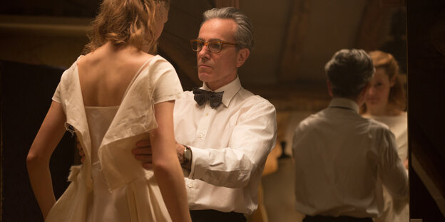 Daniel Day-Lewis passt ein Kleid an einer Frau an, sie stehen vor einem Spiegel Daniel Day-Lewis passt ein Kleid an einer Frau an, sie stehen vor einem Spiegel