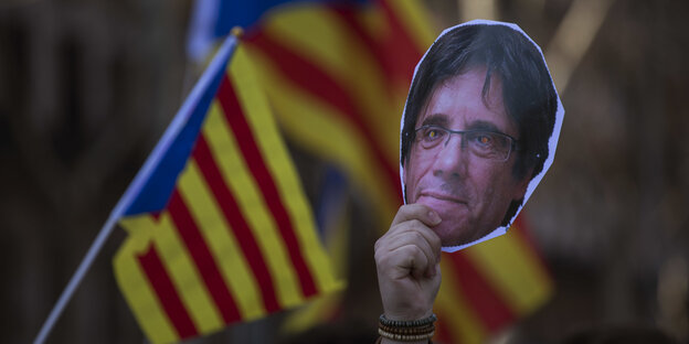 Pro-Katalanische Demonstranten halten ein papiernes Konterfei von Puigdemont hoch Pro-Katalanische Demonstranten halten ein papiernes Konterfei von Puigdemont hoch