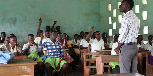 Ein Lehrer steht in einem Schulzimmer in Ghana und unterrichtet Ein Lehrer steht in einem Schulzimmer in Ghana und unterrichtet