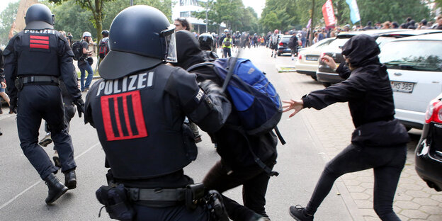 Ein Polizist mit Schlagstock schlägt auf eine Person Ein Polizist mit Schlagstock schlägt auf eine Person