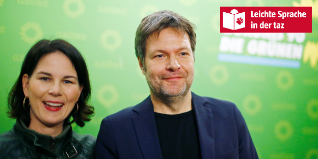 Eine Frau und ein Mann nebeneinander. Im Hintergrund eine grüne Wand Eine Frau und ein Mann nebeneinander. Im Hintergrund eine grüne Wand