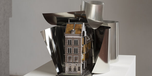 Das Modell eines Hauses steht in einer aufgebrochenen Metallform Das Modell eines Hauses steht in einer aufgebrochenen Metallform