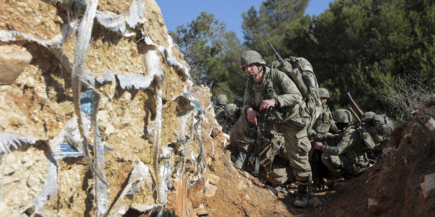 mehrere Soldaten, im Hintergrund Bäume und blauer Himmel