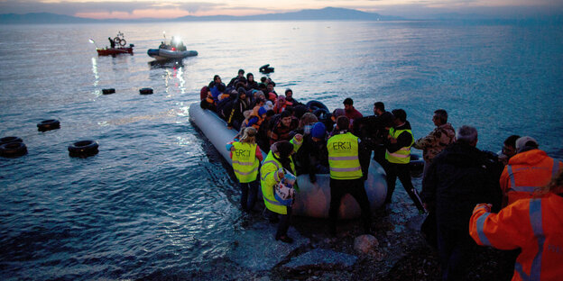 Helfer helfen Menschen aus einem Flüchtlingsboot Helfer helfen Menschen aus einem Flüchtlingsboot
