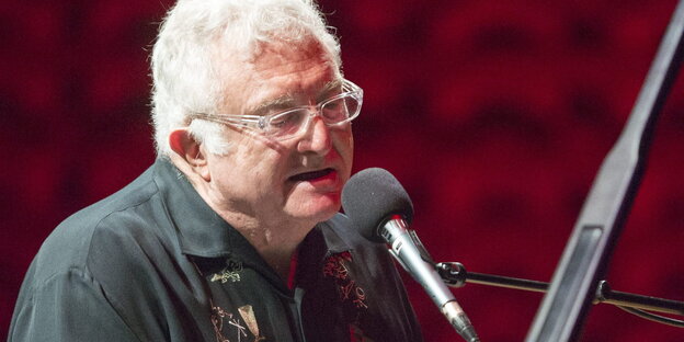 Randy Newman singt in ein Mikrofon