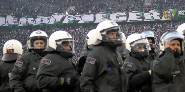 Polizistinnen und Polizisten stehen in Kampfmonitur in einem Fußballstadion Polizistinnen und Polizisten stehen in Kampfmonitur in einem Fußballstadion