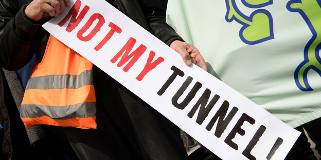 Jemand mit Leuchtweste hält ein Schild in der Hand "Not my Tunnel" Jemand mit Leuchtweste hält ein Schild in der Hand "Not my Tunnel"