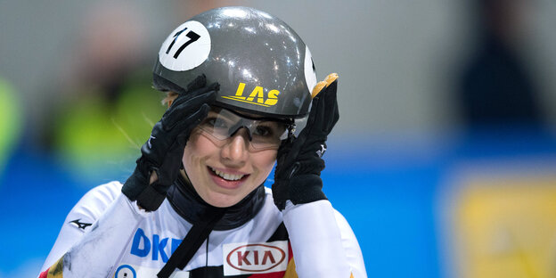 Eine Frau (Gesicht und Oberkörper) mit Sportbrille und Helm. Mit ihren Händen hält sie den Helm. Eine Frau (Gesicht und Oberkörper) mit Sportbrille und Helm. Mit ihren Händen hält sie den Helm.