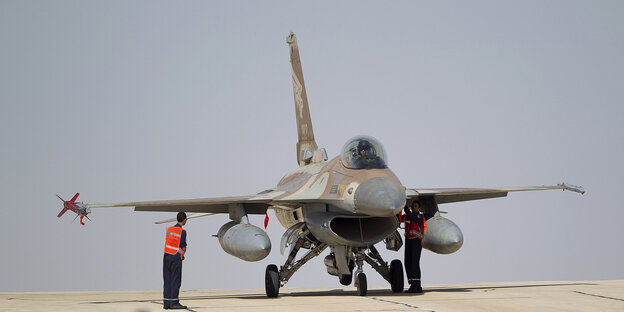 ein startbereiter Kampfjet auf einem Flugfeld, daneben ein Navigationshelfer ein startbereiter Kampfjet auf einem Flugfeld, daneben ein Navigationshelfer