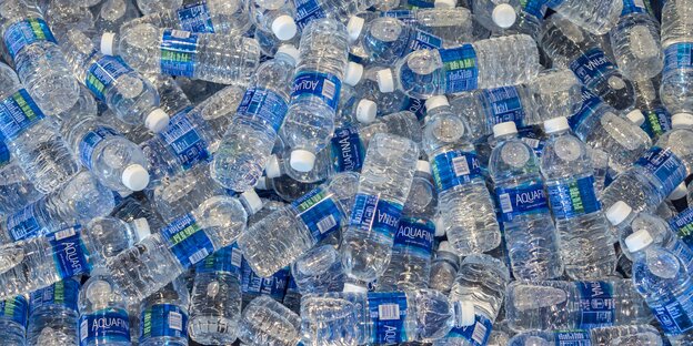 Plastikwasserflaschen mit blauen Etiketten stapeln sich übereinander Plastikwasserflaschen mit blauen Etiketten stapeln sich übereinander