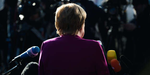 Angela Merkel steht im Dunkeln vor Mikrofonen Angela Merkel steht im Dunkeln vor Mikrofonen