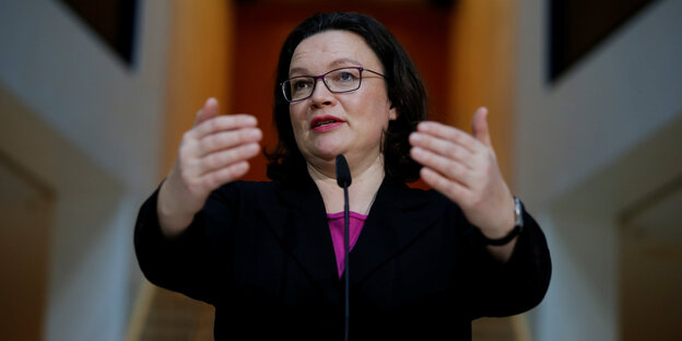 Andrea Nahles hebt die Hände an einem Mikrofon