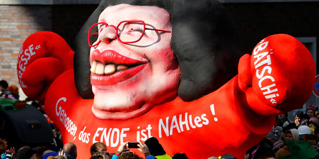 Ein Karnevalswagen zeigt eine Figur, die eine Karikatur von Andrea Nahles darstellt, daneben laufen Menschen Ein Karnevalswagen zeigt eine Figur, die eine Karikatur von Andrea Nahles darstellt, daneben laufen Menschen