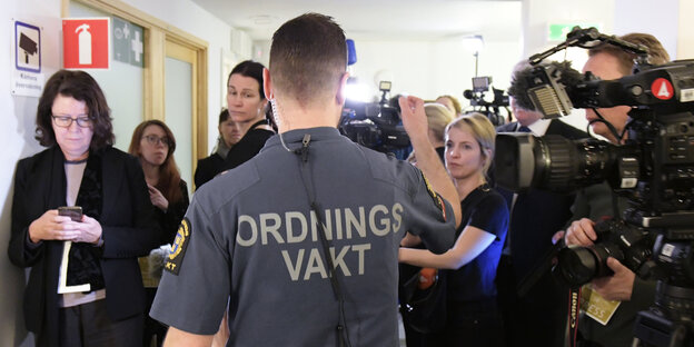 Ein Mann in Uniform vor einer Menschengruppe Ein Mann in Uniform vor einer Menschengruppe