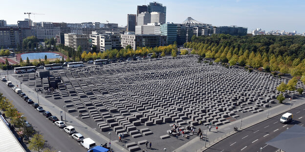 Unzählige graue Stelen stehen auf einem rechteckigen Platz. Unzählige graue Stelen stehen auf einem rechteckigen Platz.