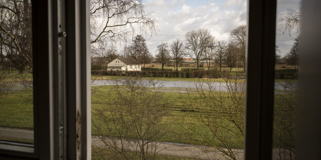 Blick aus dem Fenster auf ein fernes weißes Häuschen Blick aus dem Fenster auf ein fernes weißes Häuschen