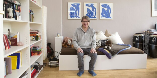 Ein Mann sitzt in Socken auf seinem Bett Ein Mann sitzt in Socken auf seinem Bett