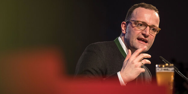 Jens Spahn spricht auf der Bühne mit einem Bier