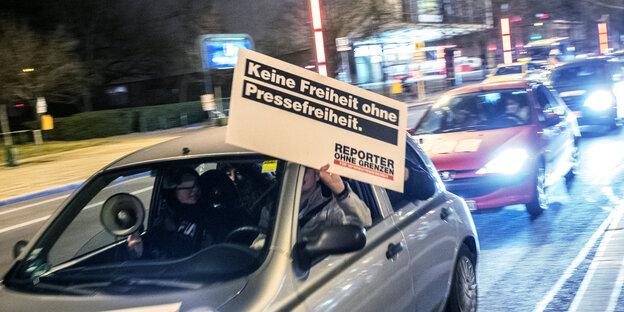 Ein Auto aus dessen Fenster jemand ein Plakat hält Ein Auto aus dessen Fenster jemand ein Plakat hält