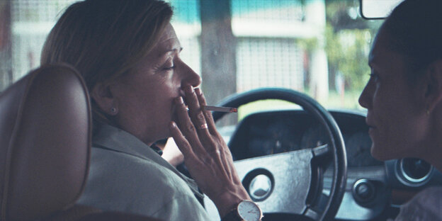 Zwei Frauen im Auto. Eine raucht eine Zigarette Zwei Frauen im Auto. Eine raucht eine Zigarette