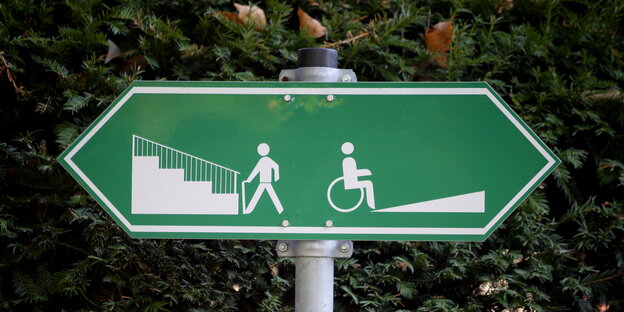 ein grünes Schild, das Pfeile nach links und rechts hat, auf der linken Seite eine Treppe und das Piktogramm eines gehenden Menschen, auf der rechten Seite eine Rampe und ein Rollstuhlfahrer ein grünes Schild, das Pfeile nach links und rechts hat, auf der linken Seite eine Treppe und das Piktogramm eines gehenden Menschen, auf der rechten Seite eine Rampe und ein Rollstuhlfahrer