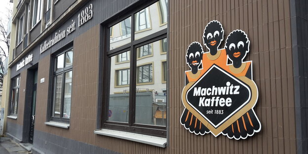 Eine braune Hausfassade mit dem Logo der Firma Machwitz. Das Logo zeigt drei Schwarze mit dicken Lippen und Glubschaugen. Eine braune Hausfassade mit dem Logo der Firma Machwitz. Das Logo zeigt drei Schwarze mit dicken Lippen und Glubschaugen.