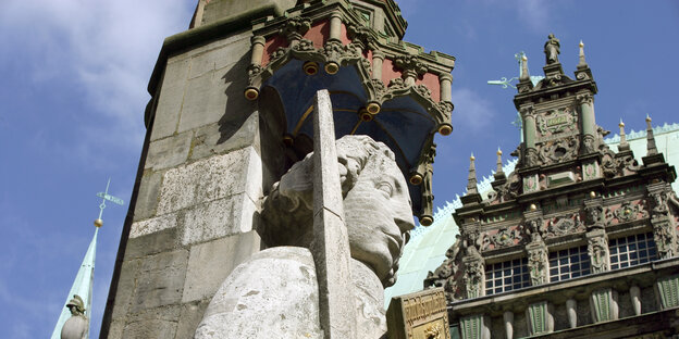 Eine Statue aus Stein zeigt einen Mann mit Schwert. Im Hintergrund steht das Bremer Rathaus. Eine Statue aus Stein zeigt einen Mann mit Schwert. Im Hintergrund steht das Bremer Rathaus.