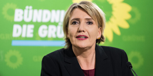 Eine Frau mit blonden kurzen Haaren vor einer grünen Wand Eine Frau mit blonden kurzen Haaren vor einer grünen Wand