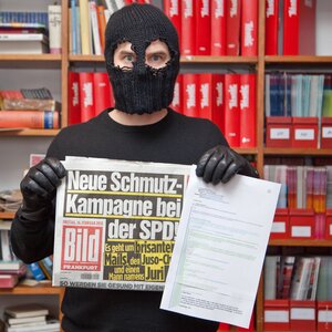 Ein maskierter Mann hält eine Ausgabe der„Bild“-Zeitung in der Hand Ein maskierter Mann hält eine Ausgabe der„Bild“-Zeitung in der Hand