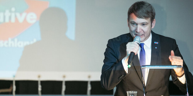 Ein Mann Anzug spricht in ein Mikrofon Ein Mann Anzug spricht in ein Mikrofon
