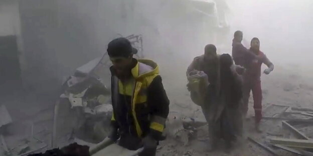 Menschen in einer staubigen und zerstörten Straße in Ost-Ghouta Menschen in einer staubigen und zerstörten Straße in Ost-Ghouta
