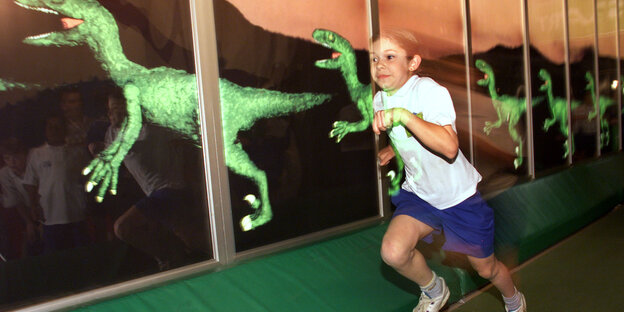 Ein Kind rennt neben einem Dinosaurierbild Ein Kind rennt neben einem Dinosaurierbild