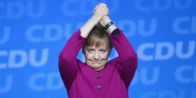Angela Merkel steht vor einer CDU-Plakatwand und hat die Hände zu einer Siegerpose erhoben Angela Merkel steht vor einer CDU-Plakatwand und hat die Hände zu einer Siegerpose erhoben