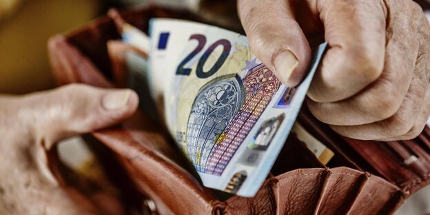 Ein älterer Menschen zieht einen 20 Euro-Schein aus seiner Geldbörse Ein älterer Menschen zieht einen 20 Euro-Schein aus seiner Geldbörse