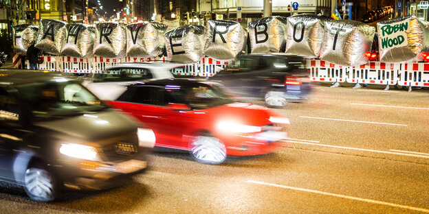 Fahrende Autos und ein Transparent mit der Forderung nach Fahrverboten Fahrende Autos und ein Transparent mit der Forderung nach Fahrverboten