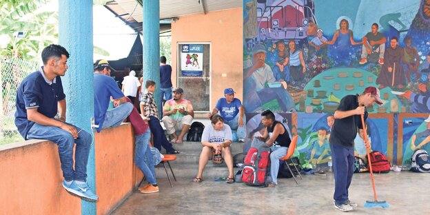 Männer, Frauen und Kinder sitzen wartend auf einer überdachten Terrasse Männer, Frauen und Kinder sitzen wartend auf einer überdachten Terrasse
