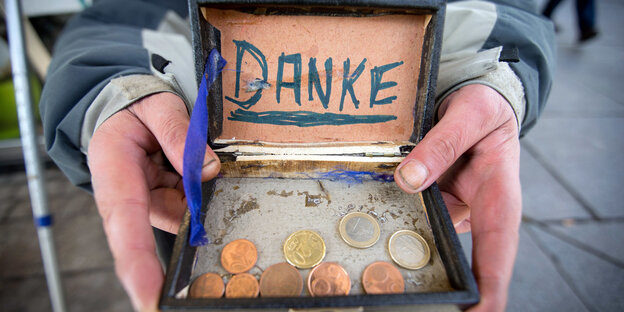 Jemand hält eine Schachtel, in der Geldmünzen liegen. Im Deckel eine Zettel mit der Aufschrift „Danke“ Jemand hält eine Schachtel, in der Geldmünzen liegen. Im Deckel eine Zettel mit der Aufschrift „Danke“