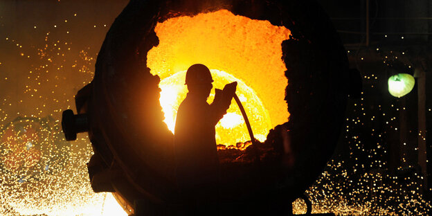 Silhouette eines Arbeiters vor einem Stahlofen Silhouette eines Arbeiters vor einem Stahlofen