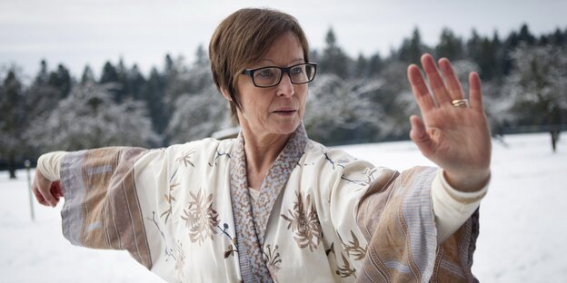 Eine Frau streckt bei Schnee die Arme raus Eine Frau streckt bei Schnee die Arme raus