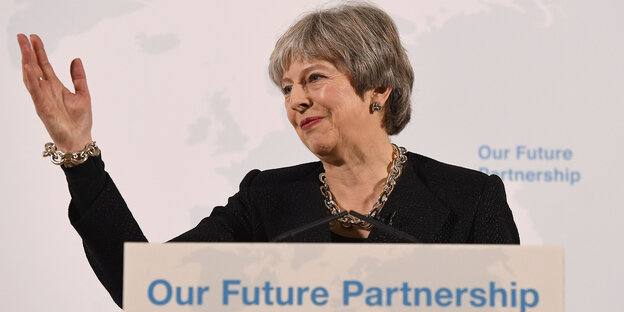 Theresa May, winkend, an einem Pult auf dem „Our Future partnership“ steht Theresa May, winkend, an einem Pult auf dem „Our Future partnership“ steht