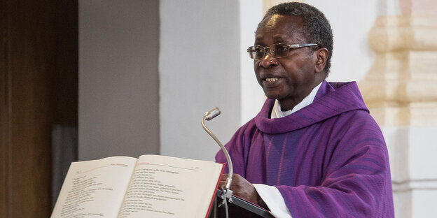 Ein Mann in Priestergewand spricht in ein Mikrofon Ein Mann in Priestergewand spricht in ein Mikrofon