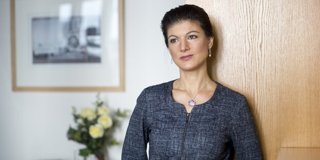 Sahra Wagenknecht lehnt sich an einen Holzschrank Sahra Wagenknecht lehnt sich an einen Holzschrank